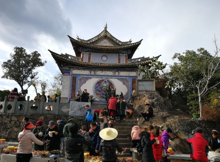 云南一个寺庙，被小吃摊包围，墙都被烧烤的油烟熏黑了！