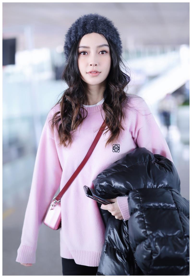 Angelababy穿粉毛衣搭毛绒帽甜美可爱 手拿羽绒服大步前行