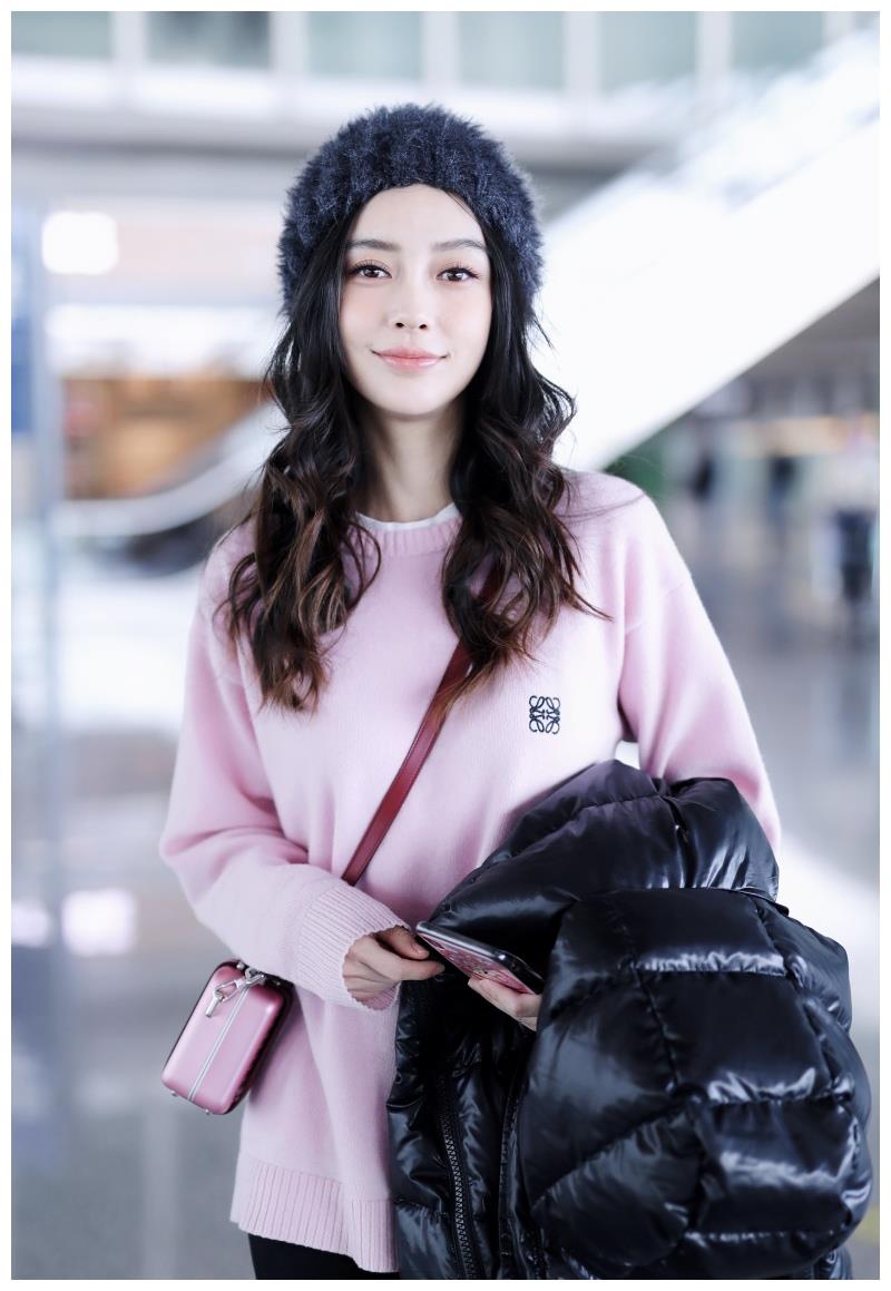 Angelababy穿粉毛衣搭毛绒帽甜美可爱 手拿羽绒服大步前行
