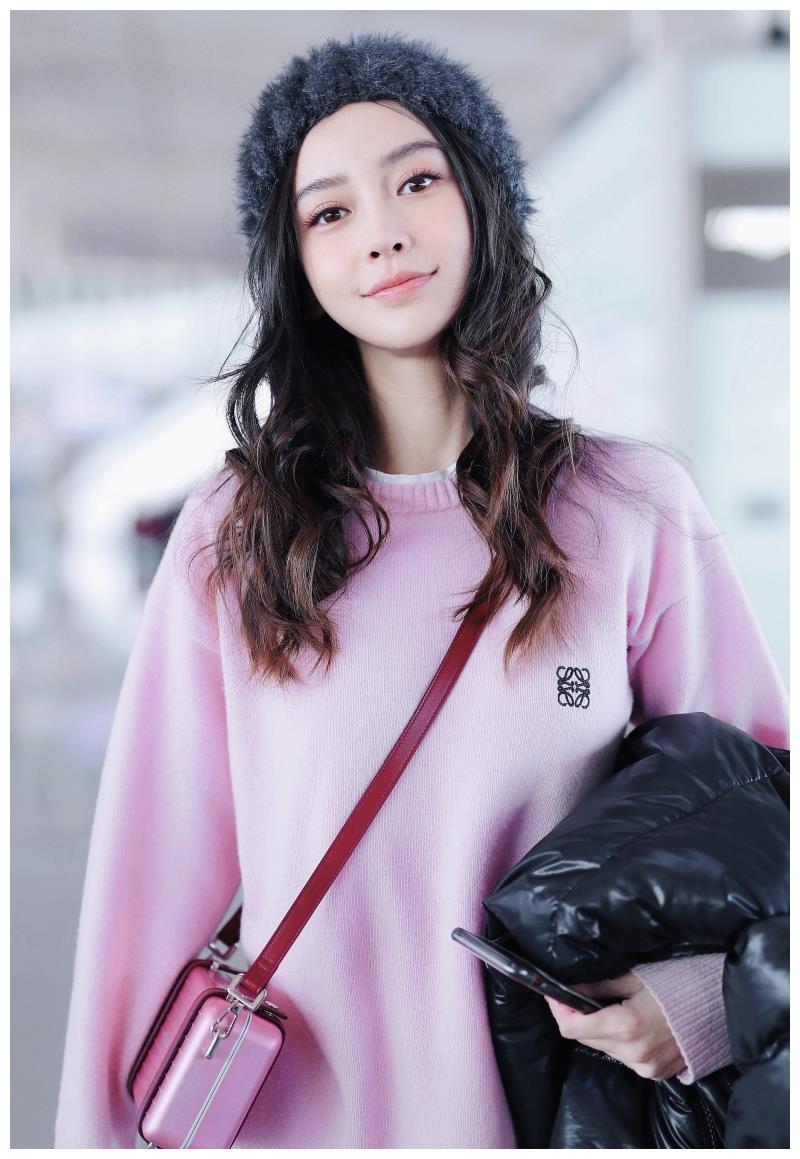 Angelababy穿粉毛衣搭毛绒帽甜美可爱 手拿羽绒服大步前行