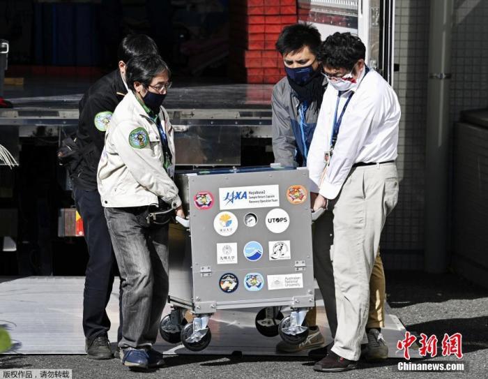 当地时间12月14日,日本神奈川相模原市,日本航空航天局(JAXA)公布由“隼鸟2号”收集并带回的小行星表面稀有样本。图为工作人员运送装有样本的箱子。