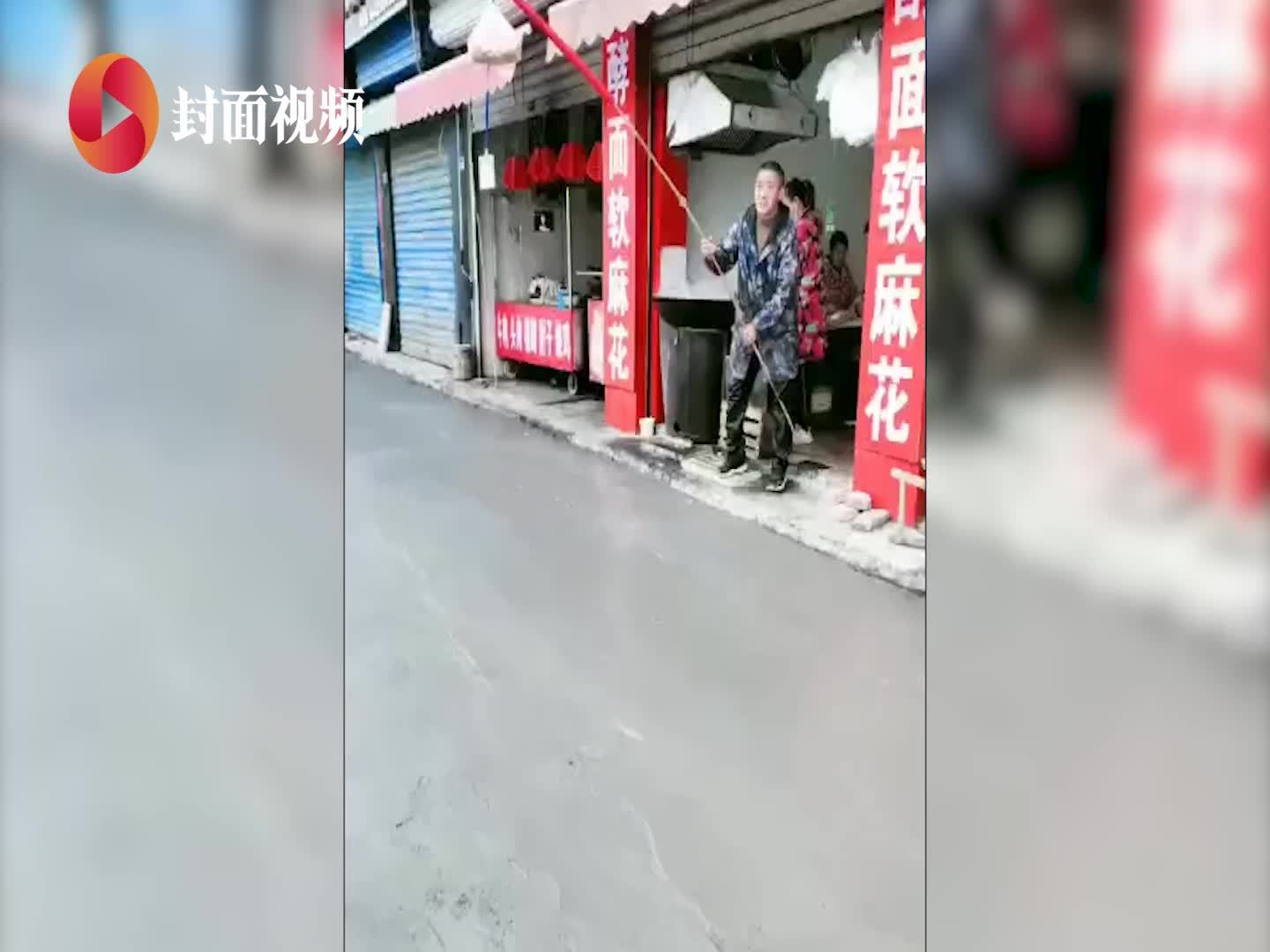 店铺门前修路 店主拿长棍挑商品和付款码给顾客隔空售卖